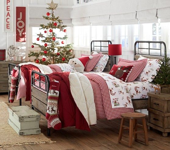a Christmas tree decorated with red ornaments, red and white signs on the wall and printed Christmassy bedding for a holiday feel