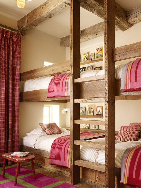 a cozy rustic kids' room with four built-in bunk beds, with a ladder and pink and white bedding, with matching curtains and a rug