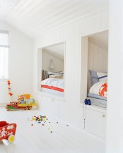 a white Scandinavian kids’ room with built-in bunk beds, with bright bedding, lots of natural light and colorful toys is ultimate