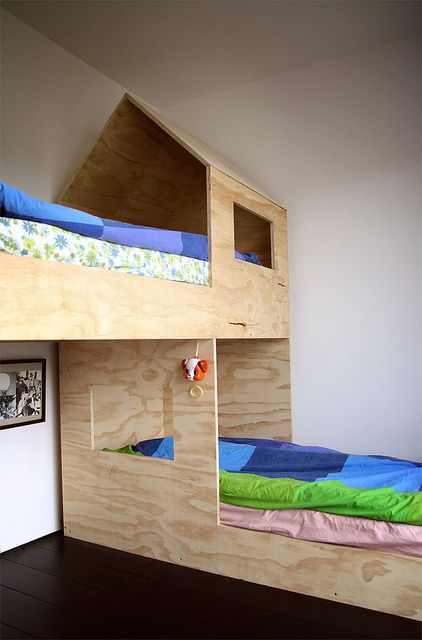 a small kids' room with a plywood bunk bed placed at 90 degrees, with bright bedding is a cool space for kids