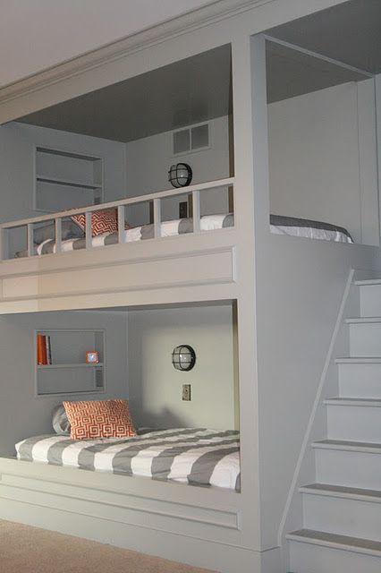 a grey kids' room with built-in bunk beds with printed bedding and a ladder is a stylish and cozy space to be in
