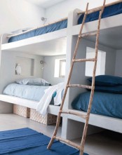 a coastal space with white built-in bunk beds, with blue and navy bedding, with a ladder and navy rugs is a stylish space with love to the sea