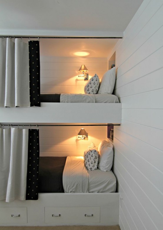 a white kids' room with built-in bunk beds, black and white bedding and curtains, sconces on the walls for more coziness