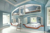 a coastal light blue kids’ room with built-in bunk beds, a ladder and several windows to flood the space with light