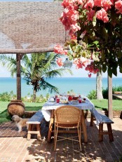 a bright summer terrace with lots of blooms and palm trees, with wooden furniture and rattan chairs, with a gorgeous sea view
