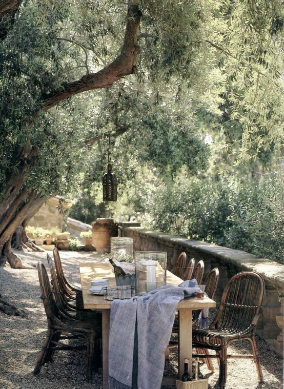 a summer terrace with a dining space in Mediterranean style, with wooden and rattan furniture and neutral textiles