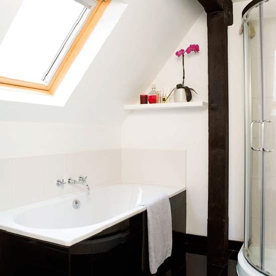 a chic contrasting bathroom with white tiles and a bathtub clad with black tiles plus a skylight for more natural light