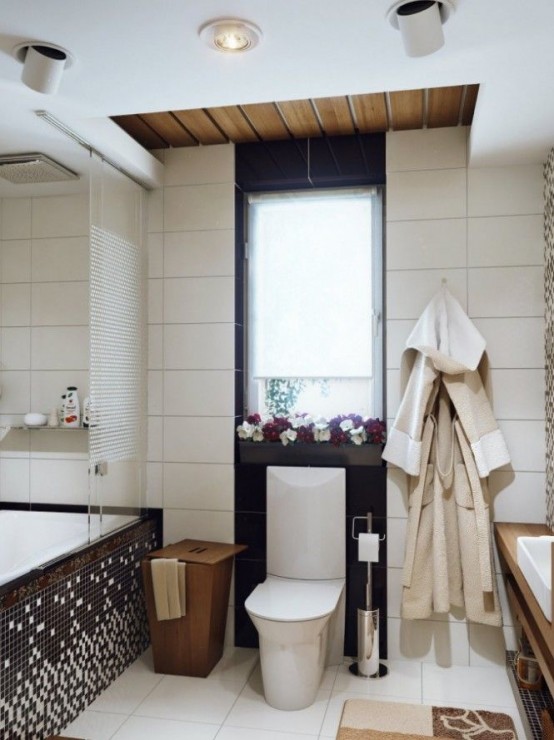 a contemporary bathroom with black and white tiles, a floating wooden vanity, a tub clad with mosaic tiles and a wooden bucket