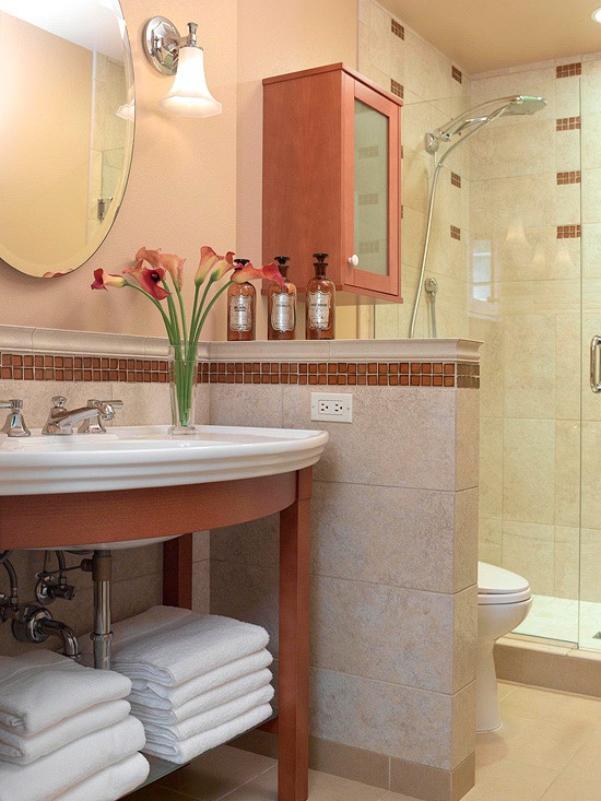 a small traditional bathroom with a redwood vanity and a sink, a cabinet on the wall, a shower space and a half wall