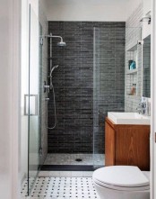 a small modern bathroom with a floating vanity, a shower space with a dark tile wall and a mosaic tile floor