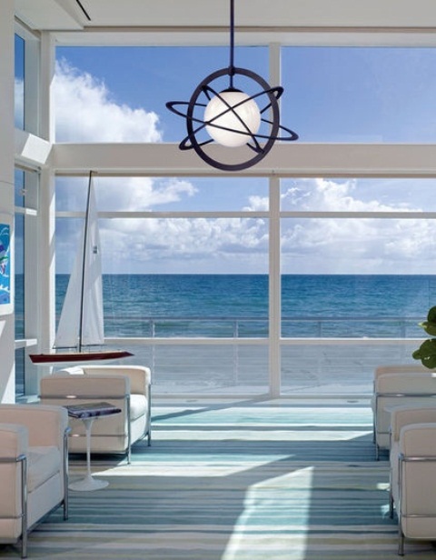 a seaside patio in blues and white, with white furniture, a pendant lamp and blue and white textiles is lovely