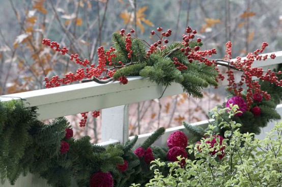 lush greenery, evergreens, berries and red Christmas ornaments to decorate the balcony for the holidays with a natural feel