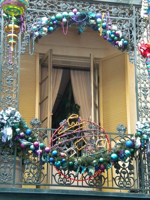 a balcony fully decorated with colorful Christmas ornaments, bows, evergreens and ornaments made of lights