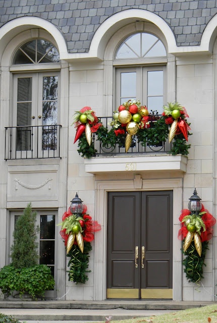 bright holiday balcony decor done with evergreens, oversized gold, green and red ornaments and red bows