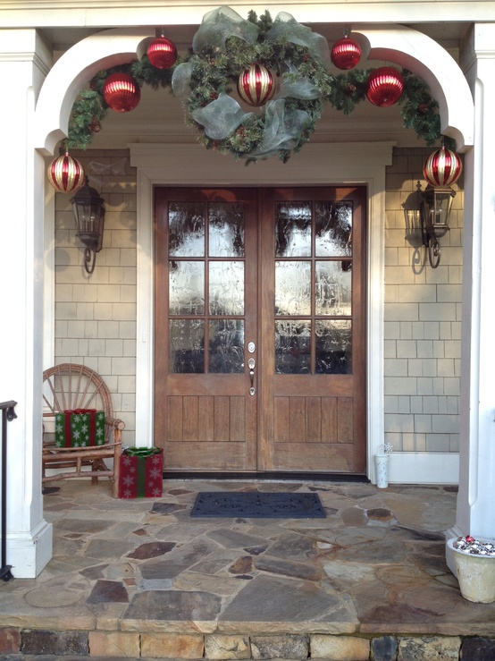 a evergreen garland with red and gold ornaments, an evergreen wreath with sheer ribbons, red and green gift boxes is cozy