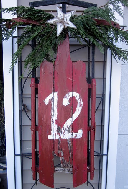 a vintage red sleigh with a house number, fir branches and a star is a chic idea for a rustic porch