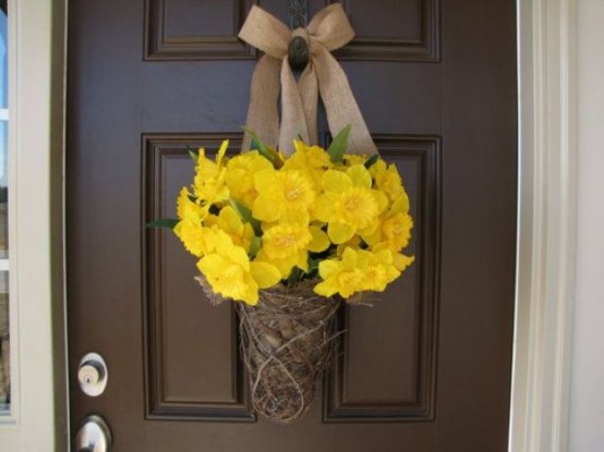 a rustic door decoration of daffodils, with a vine base and a burlap bow on top is a classic farmhouse decoration