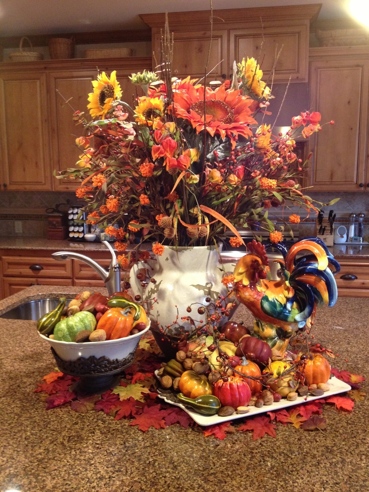 a white jug with bright fall branches, blooms and berries, faux pumpkins and gourds for decorating the table