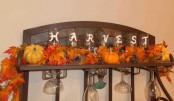 faux leaves, pumpkins and pinecones placed on a shelf is a very cool rustic-inspired idea