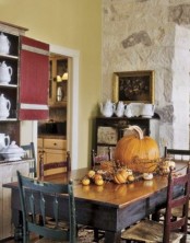 a cool and traditional fall centerpiece of a large pumpkin and some smaller pumpkins plus berries and branches