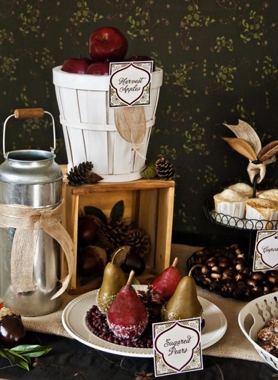 a fall party food station styled with pinecones, apples, moss, burlap and a bucket for a cozy rustic feel