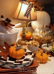 checked black and white plates, faux pumpkins with plaid ribbons and dried fall leaves for styling a tablescape for a party