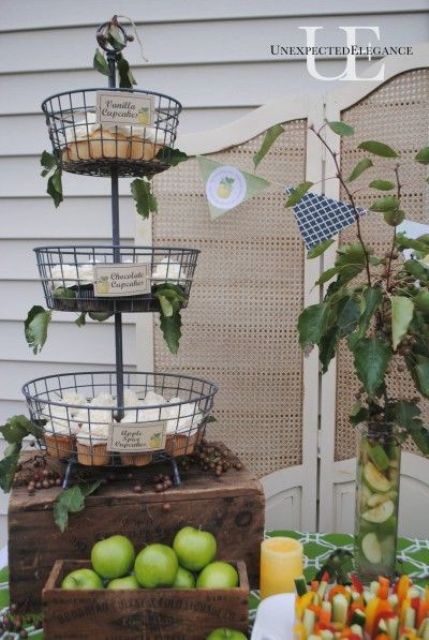 greenery arrangements, a green bunting, a rattan screen and a green tablecloth for decorating a fall party food station