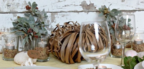 pale greenery, candles in glasses with seeds, a pumpkin made of paper ribbons for fall party decor