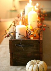 a wooden box with berries, pumpkins, candles and some pumpkins around for a rustic feel