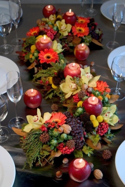 a fall centerpiece of fruits, berries and candles put into apples is a cool and cozy idea