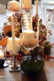 a classic fall table setting with candles, faux pumpkins, pinecones, berries and other fall stuff