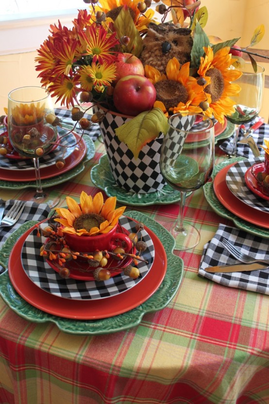 a bright tablescape with a plaid tablecloth, colorful plates and a bold centerpiece of fall blooms, leaves and apples