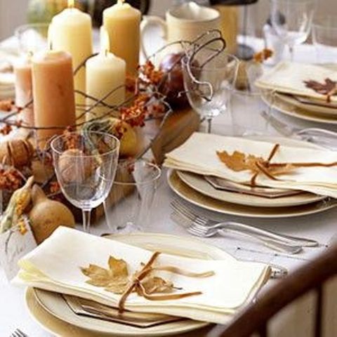 a natural fall tablescape with lots of candles, fall leaves and vine and faux fruits and berries