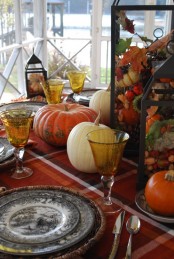 a bold traditional fall tablescape with printed textiles, plates, woven placemats and lanterns filled with nuts and acorns plus natural pumpkins