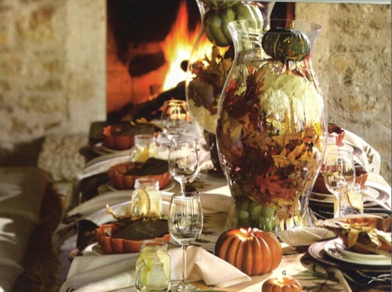 a vintage-inspired tablescape with pumpkin plates, faux pumpkins, fall leaves and large glass jars with fall leaves
