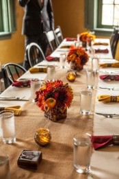 a fall tablescape spruced up with bold napkins, bold blooms and candles in candleholders