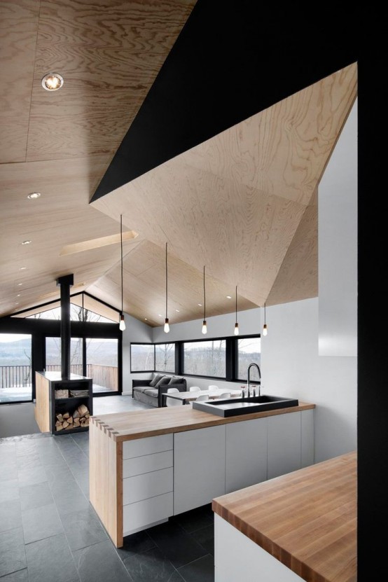 a unique minimalist kitchen done in white, black and light stained wood, a sculptural geometric ceiling is a gorgeous idea and a stylish statement