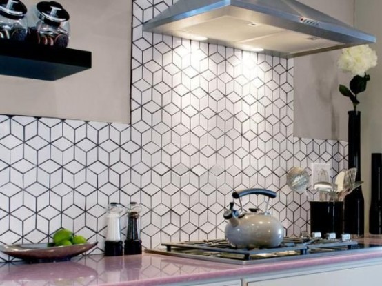 a sleek neutral kitchen with a pink countertop and a black and white geotric tile backsplash and stainless steel appliances