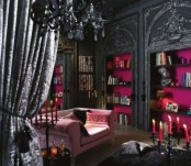 a bold and catchy Gothic living room with black molding walls and open shelves with fuchsia backing, a pink sofa, black curtains and a chandelier