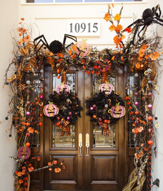 a super bright Halloween front door decorated with black spiders, bright leaves, plaid ribbons, jack-o-lanterns, ornaments and skulls