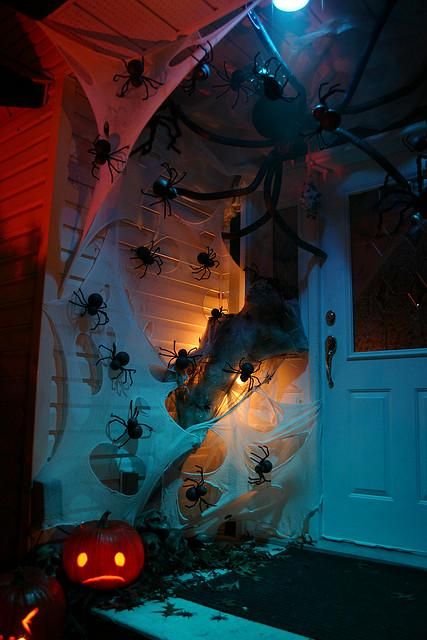 spooky Halloween front door decor with lots of spiders, spiderweb and a jack-o-lantern is a very cool and fresh idea