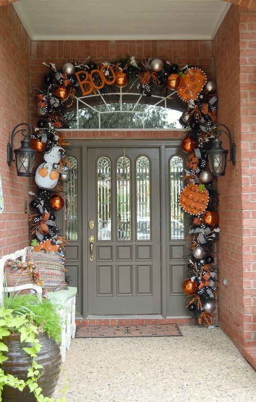 a Halloween front door decorated with black and orange pumpkins, ornaments, letters, bows and other stuff looks rather Halloween-like