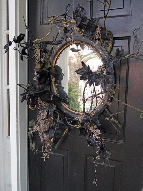a vintage mirror with twigs and black leaves is a cool alternative to a usual Halloween wreath and it looks much more creative