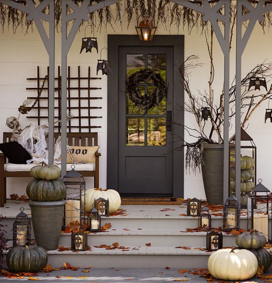 a rustic Halloween porch with natural green and white pumpkins, branches, bats and a black wreath on the front door