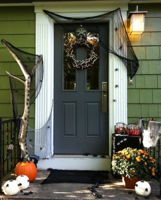 a Halloween porch styled with pumpkins, bold blooms, a black wreath and black spiderweb is a very cool idea for Halloween