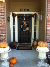 a simple Halloween porch styled with blooms and pumpkins plus a black and orange printed bunting is a very easy idea