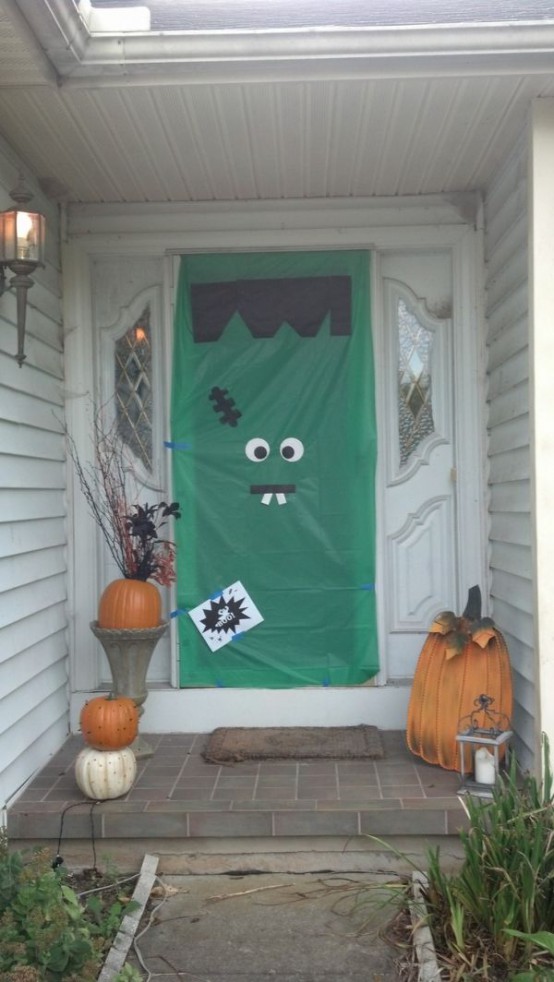 Halloween front door decor turned into a monster and with real and faux pumpkins and branches is a cool idea