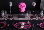 a modern glam pink and black Halloween tablescape with a printed runner, skulls, pink plates and black linens is a fun and bold idea