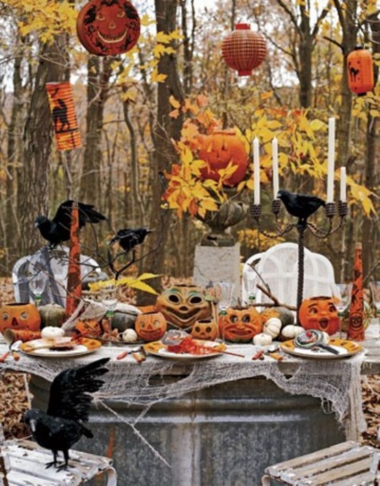 an outdoor Halloween tablescape with jack-o-lanterns, fall leaves, candles, elegant porcealin, crows and cheesecloth