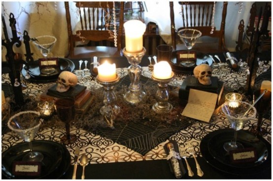 a black and white Halloween tablescape with black plates, printed textiles, candles, skulls, spiderwebs and black candelabras